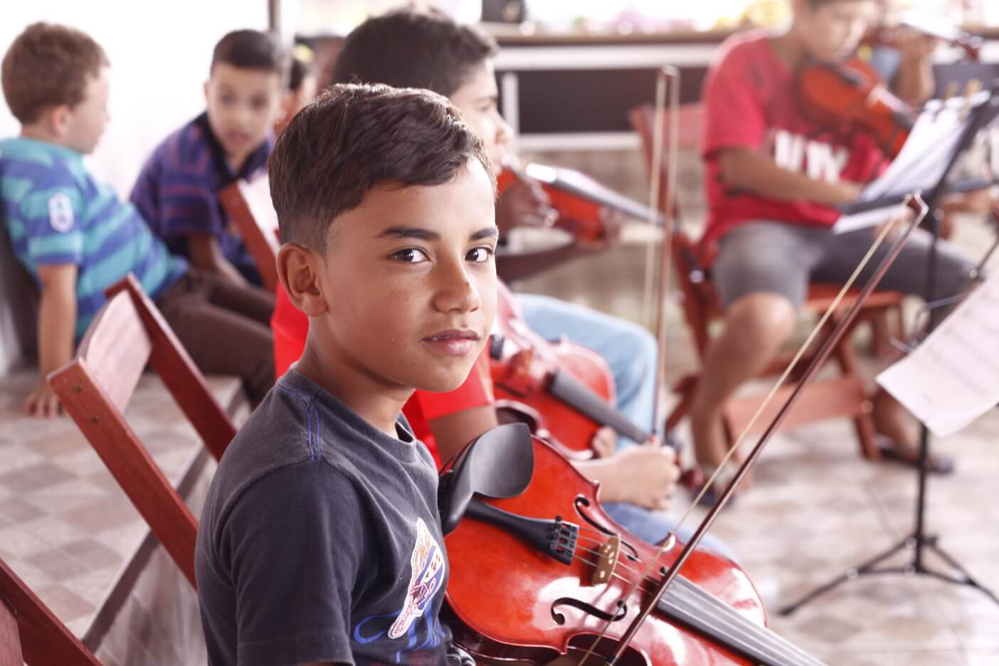 Criança sorrindo durante uma atividade de música apoiada pelo Movimento Redenção